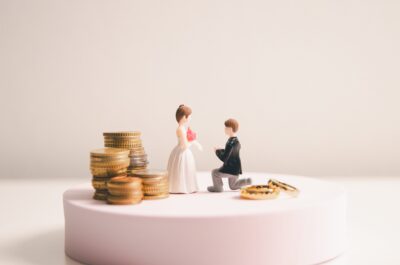 Man and Woman on wedding cake surrounded by different amounts of money, symbolising pre-nuptial agreement