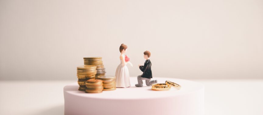 Man and Woman on wedding cake surrounded by different amounts of money, symbolising pre-nuptial agreement